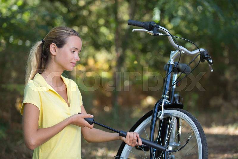 Girl pumps up bicycle tires, stock photo
