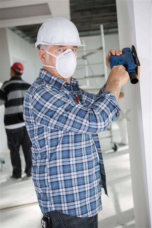 Senior worker grinding house wall, stock photo