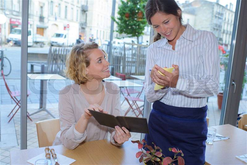Smiling woman with menus at restaurant, stock photo