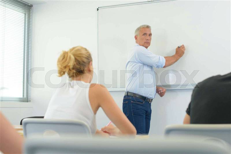 Male teacher listening to students at adult education class, stock photo