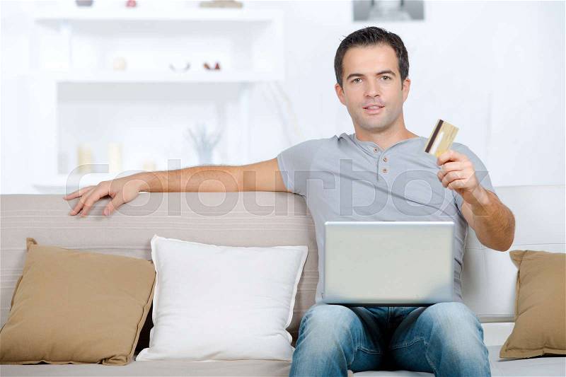 Man using laptop and credit card to buy online, stock photo