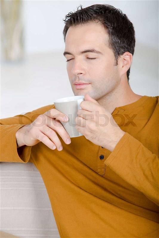Attractive guy is enjoying hot beverage, stock photo