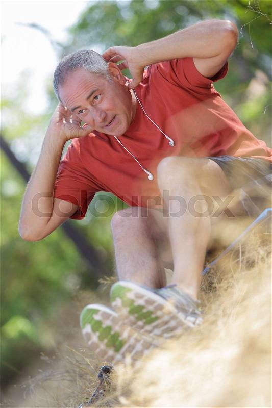 Middle age man doing sit-ups outdoor, stock photo
