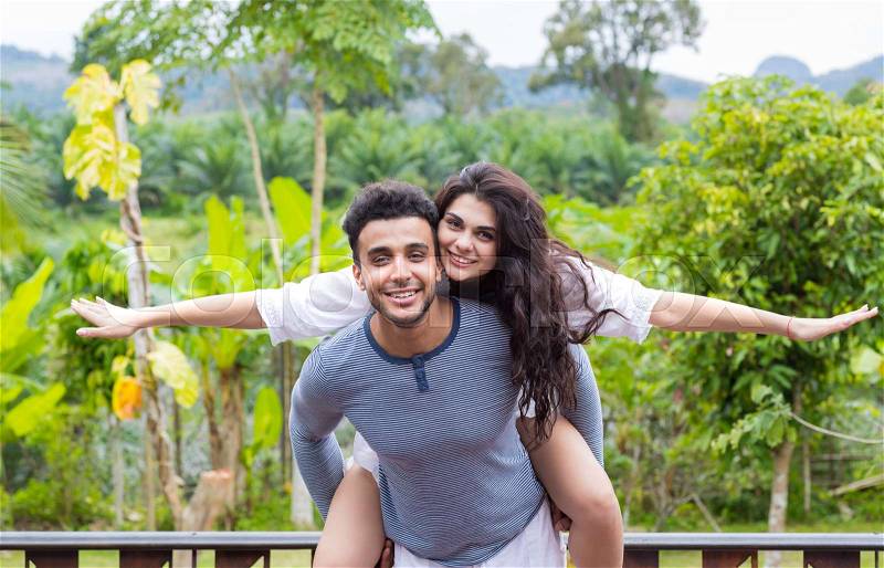Happy Latin Man Carry Woman On Back, Young Couple Over Green Tropical Rain Forest Landscape Smiling Lovers Having Fun, stock photo