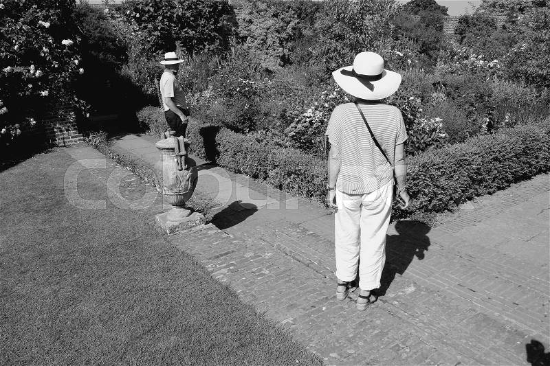 The retired couple, man and wife are posing in one of the gardens of Sissinghurst Castle in England in the summer in black and white, stock photo