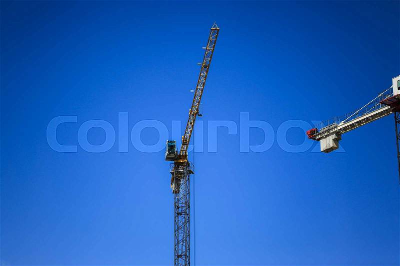 Construction concept. A new building under construction against the sky. Blue background. New urban city. Machinery, cranes and builders on scaffolding. Heavy industry and safety at work, stock photo
