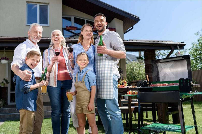 Big happy family with beverages looking aside while having barbecue together, stock photo