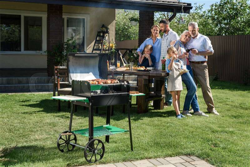 Family spend time together while having barbecue with grill at yard , stock photo