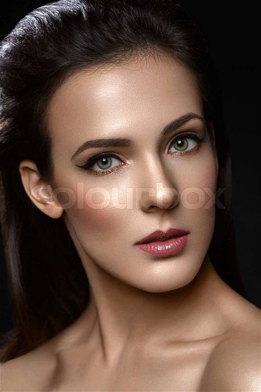 Beautiful young woman with cat eye liner make up. Beauty shot on black background. Copy space, stock photo