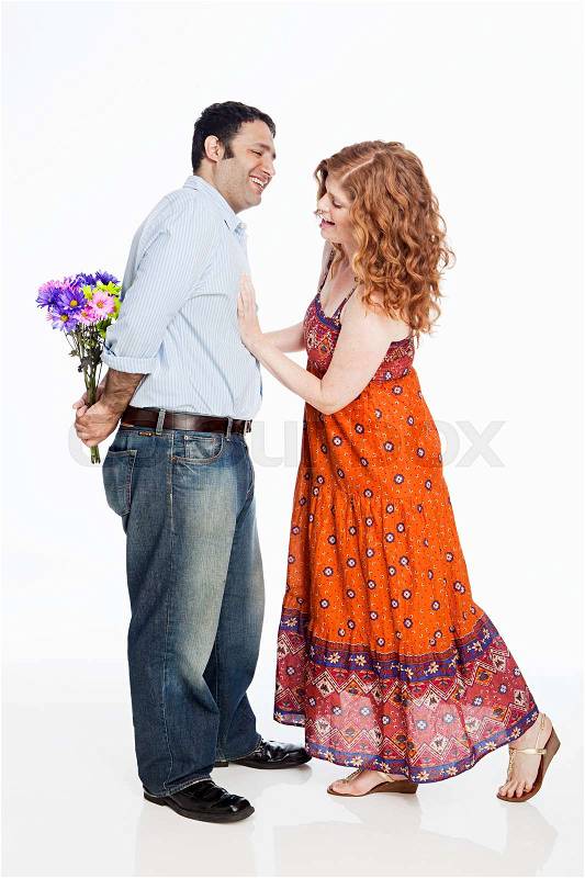 Woman looking for flowers behind man\'s back against white background, stock photo