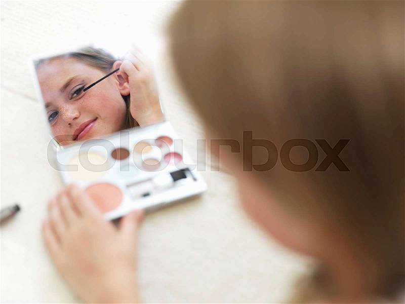 Girl in mirror putting on make-up, stock photo
