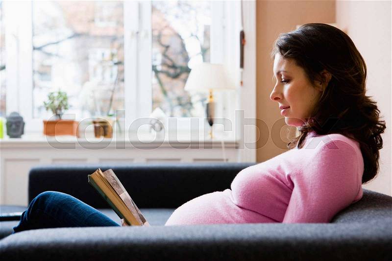 Pregnant woman reading a book, stock photo