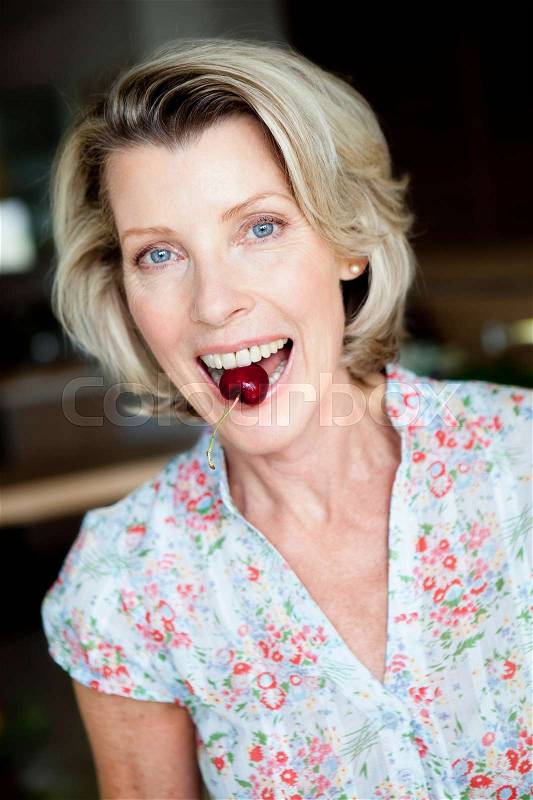 Senior Woman with Cherry between teeth, stock photo
