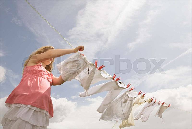 Girl putting clothing on a washing line, stock photo