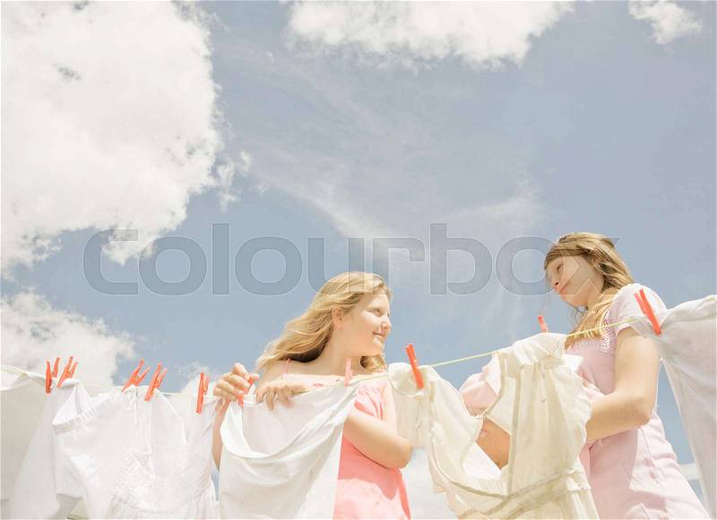 Girls putting washing on a line, stock photo