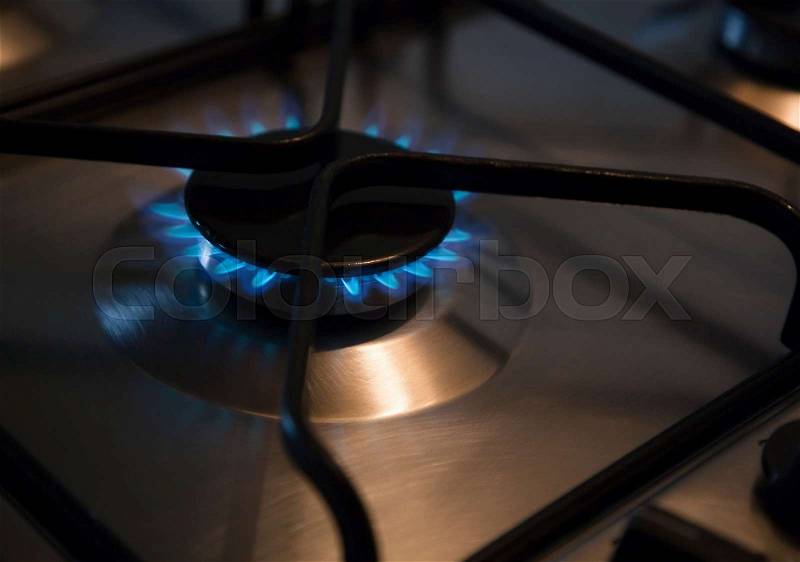 Lit gas ring on oven hob, stock photo