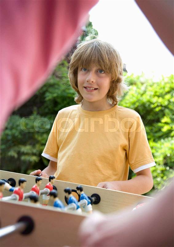 Boy (10-12) playing table football, stock photo