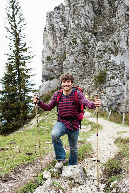 Man with hiking poles on mountain trail, stock photo