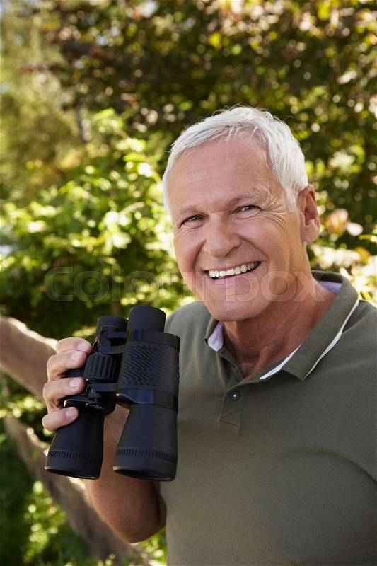 Senior man holding binoculars, stock photo