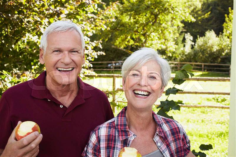 Senior couple eating apples smiling, stock photo