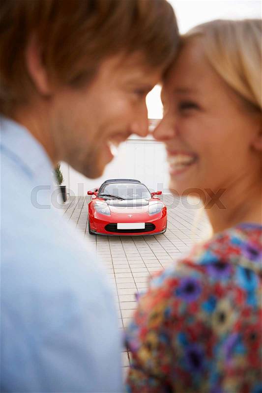 Couple close, electric car in background, stock photo
