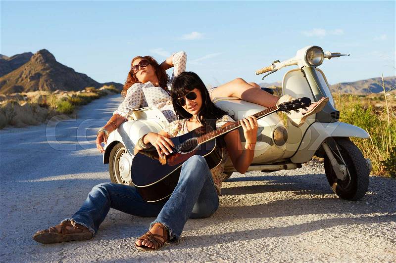 Women resting by road with motorbike, stock photo