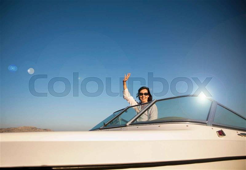 Woman waving on speedboat, stock photo