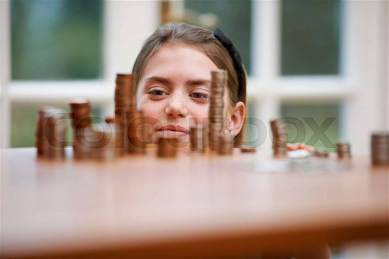 Girl looking at piles of money, stock photo