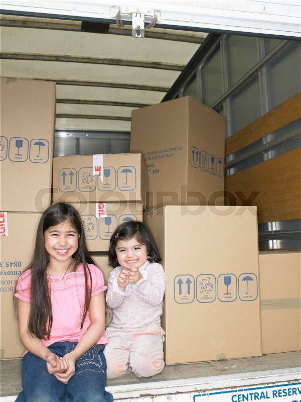 Girls sitting in moving van, stock photo