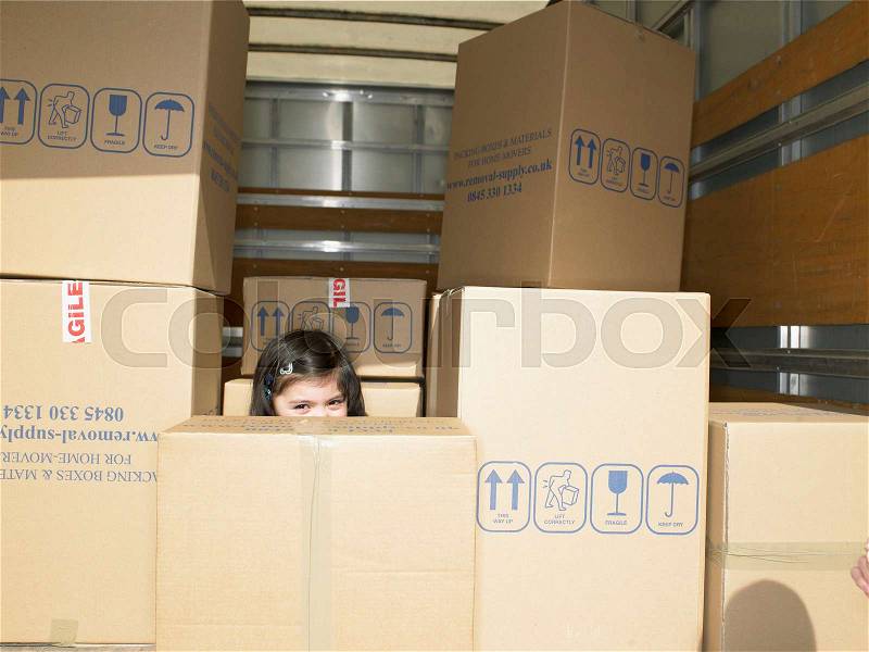 Girl hiding in boxes in moving van, stock photo