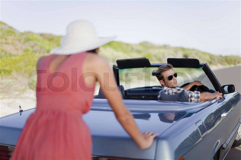 Woman pushing car as boyfriend steers, stock photo
