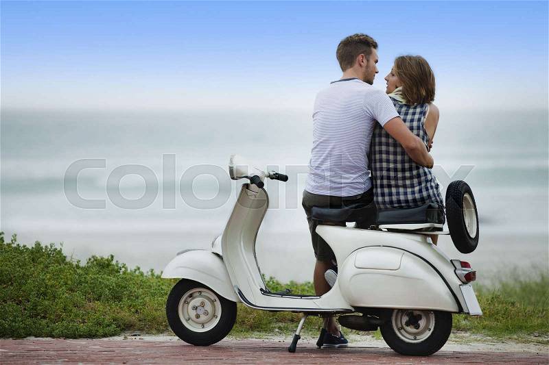 Couple sitting on scooter together, stock photo