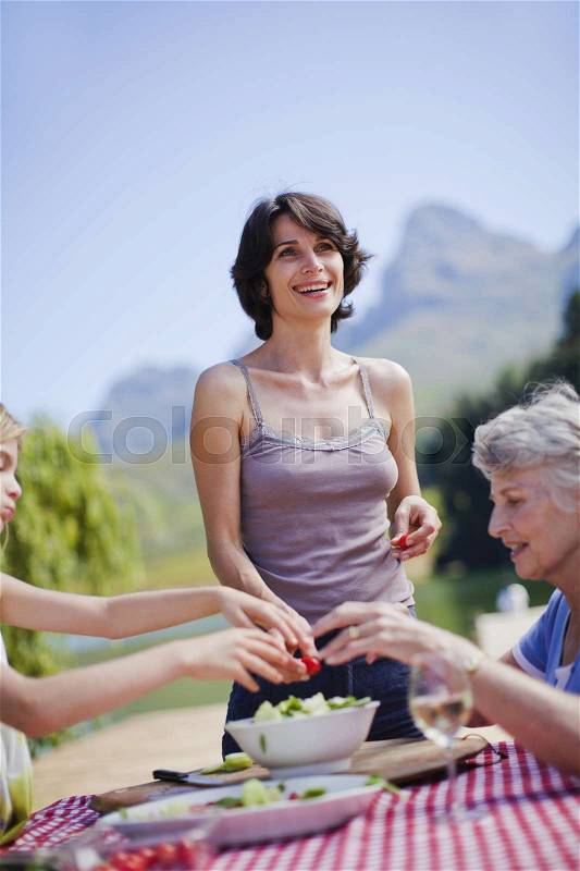 Mother making picnic lunch at table, stock photo
