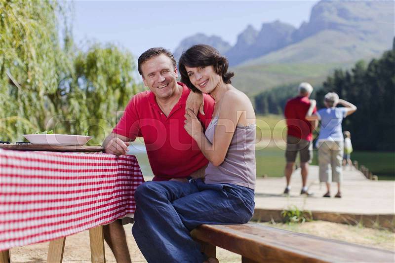 Couple sitting at picnic table together, stock photo