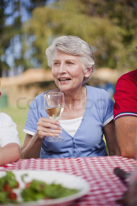 Older woman drinking at picnic table, stock photo