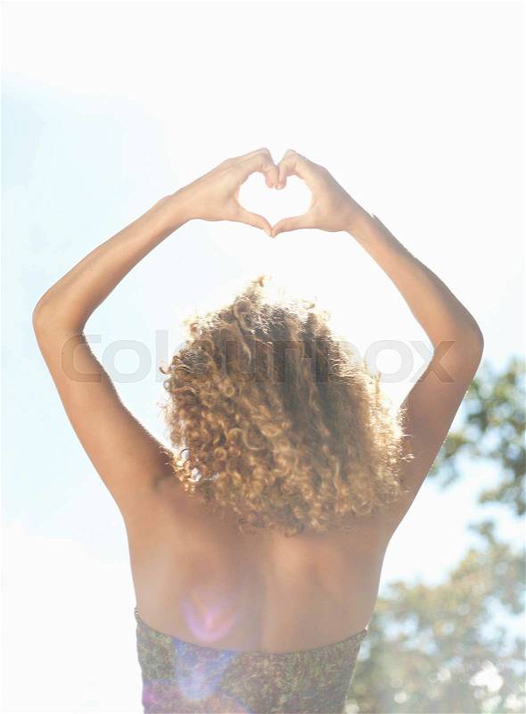 Woman making heart shape with hands, stock photo