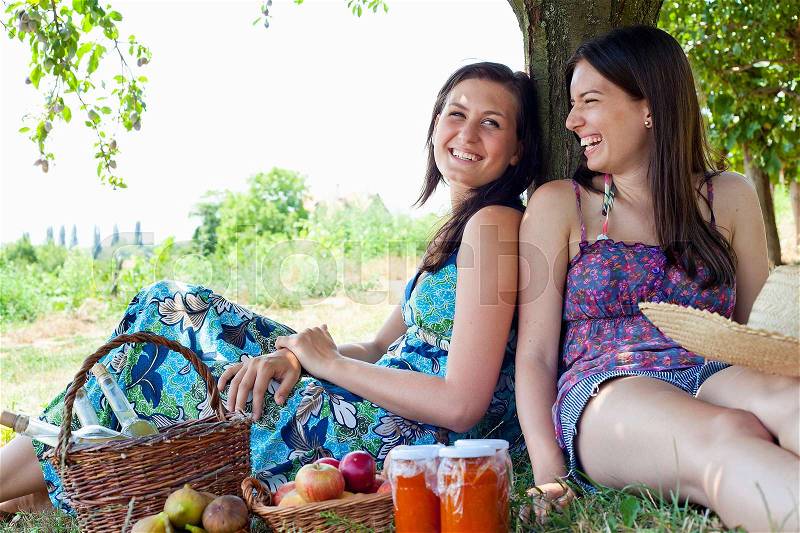 Smiling women picnicking in orchard, stock photo