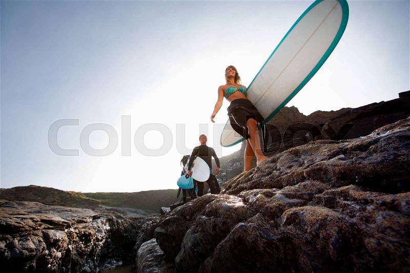 Three people carrying surfboards, stock photo