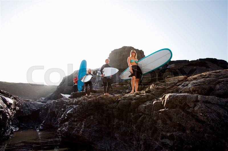 Four people carrying surfboards, stock photo