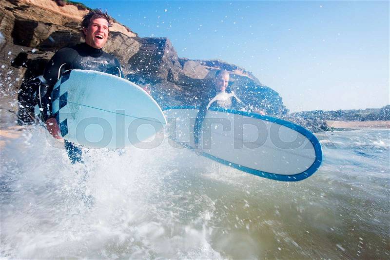 Two men running into the water with surf, stock photo