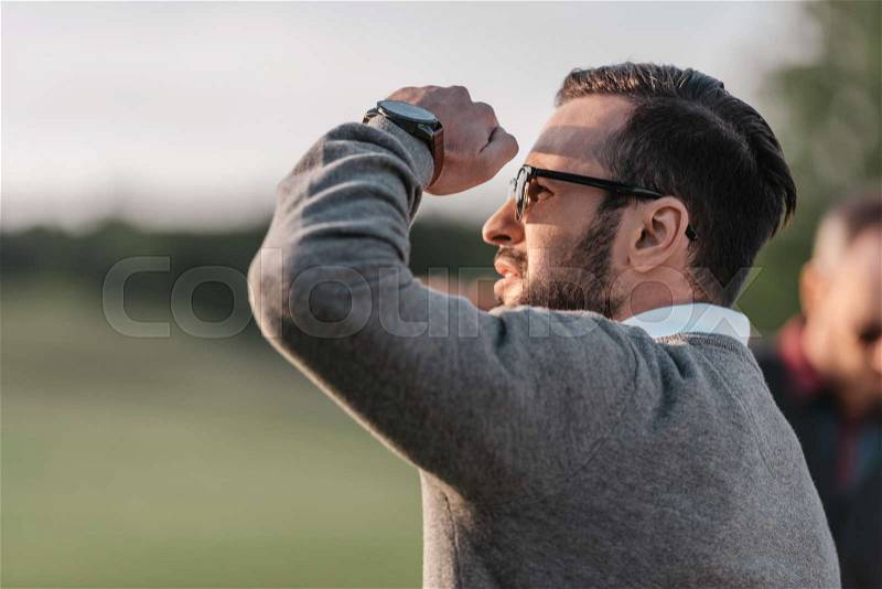 Portrait of young handsome man in sunglasses and watch looking away , stock photo