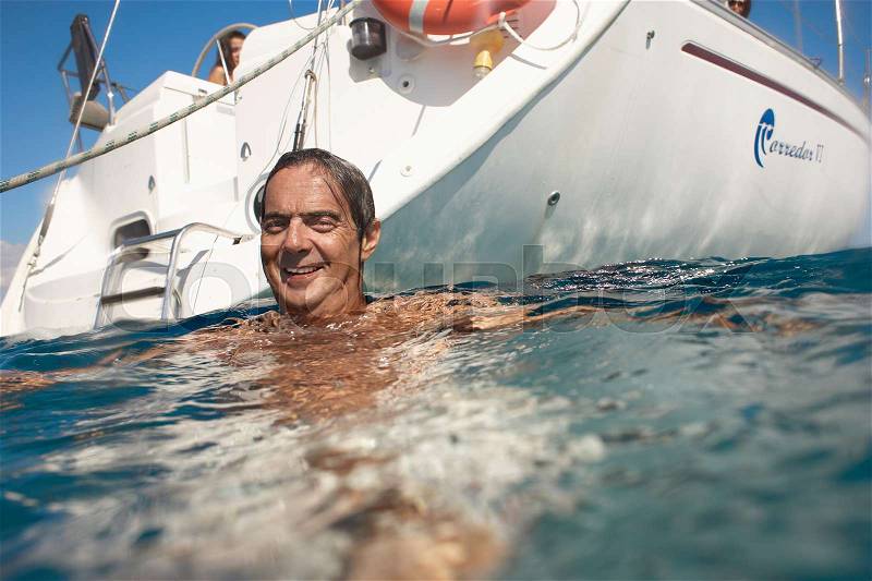 Mature man swimming in sea by yacht, stock photo