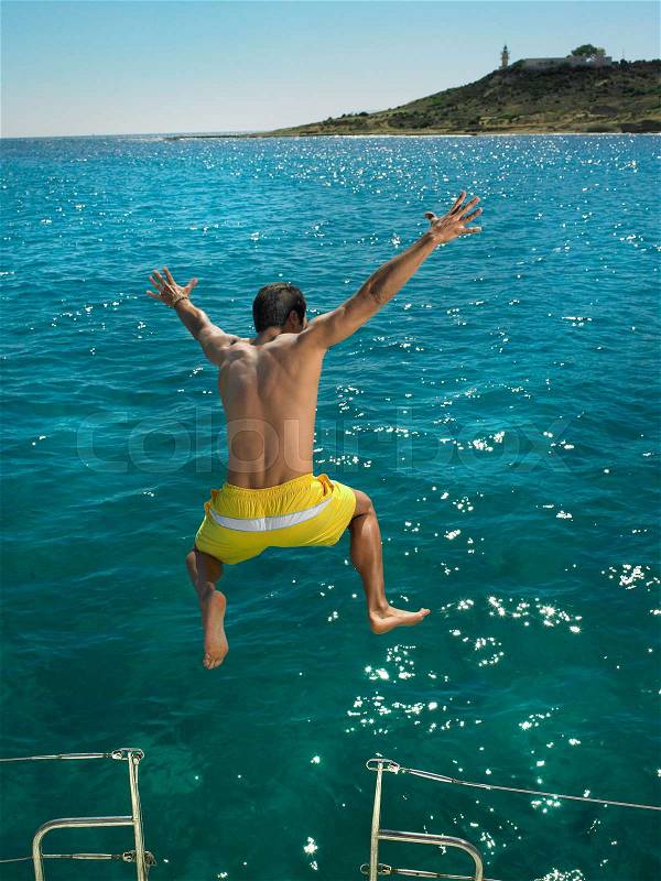 Man jumping into sea from boat, stock photo