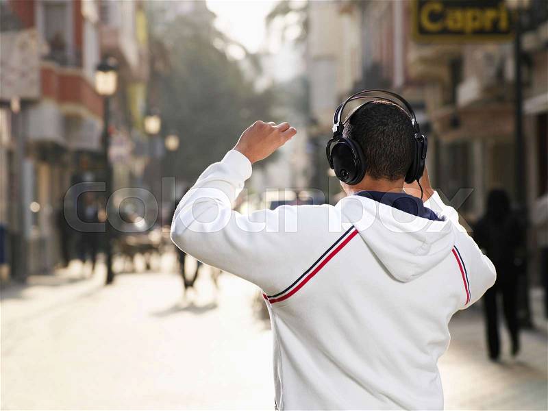 Young man in street wearing headphones, stock photo