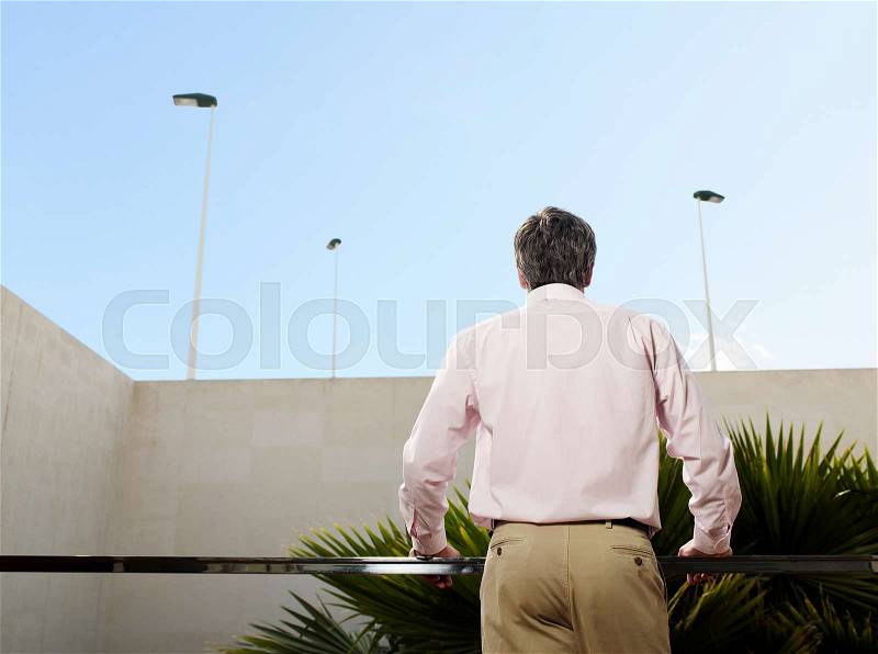 Man standing on balcony rear view, stock photo