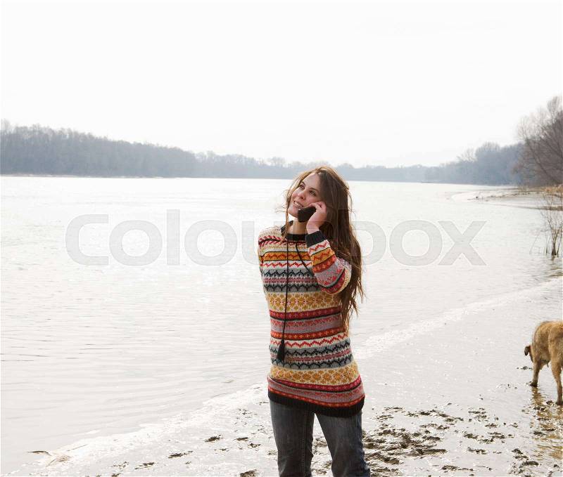 Young woman walking dog on phone, stock photo