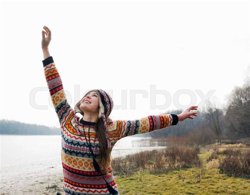 Young woman by river with arms out, stock photo