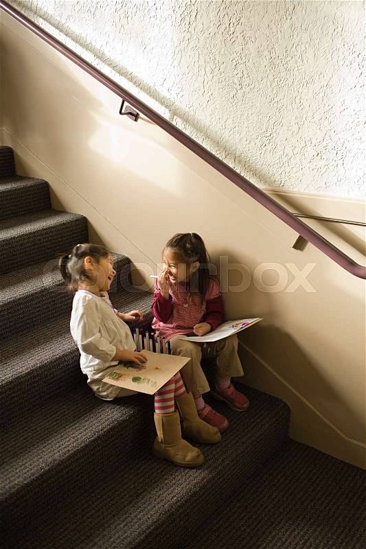 Girls sat on a step drawing and laughing, stock photo