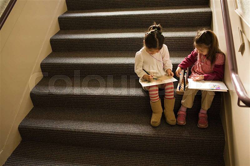Girls sat on a step drawing, stock photo