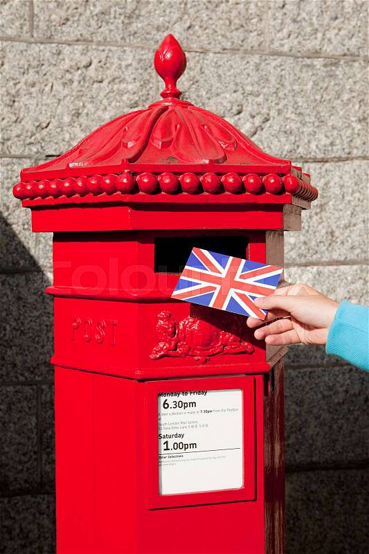 Person putting postcard in post box, London, stock photo